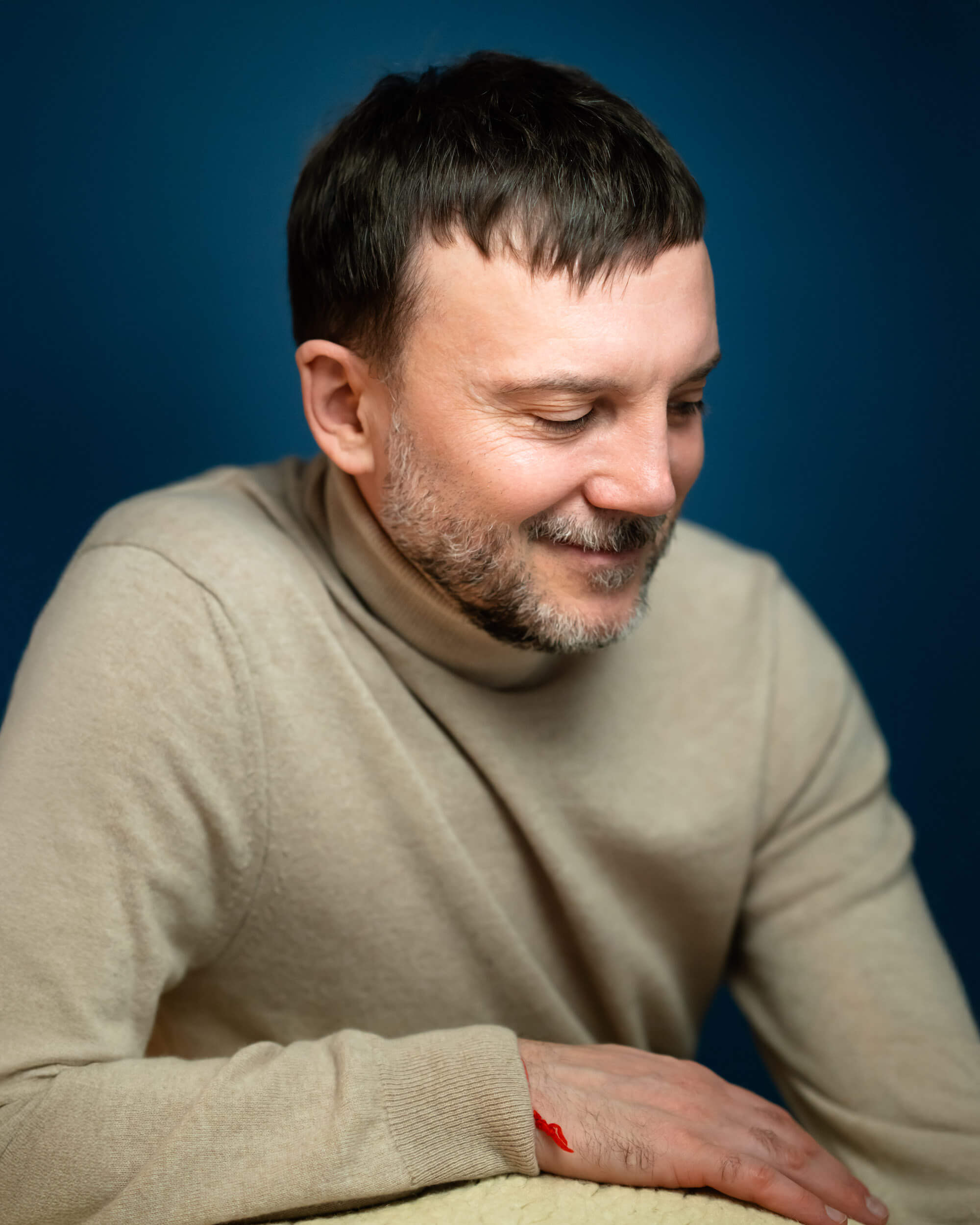 in Pullover , schaut nach links unten und lacht freundlich dabei